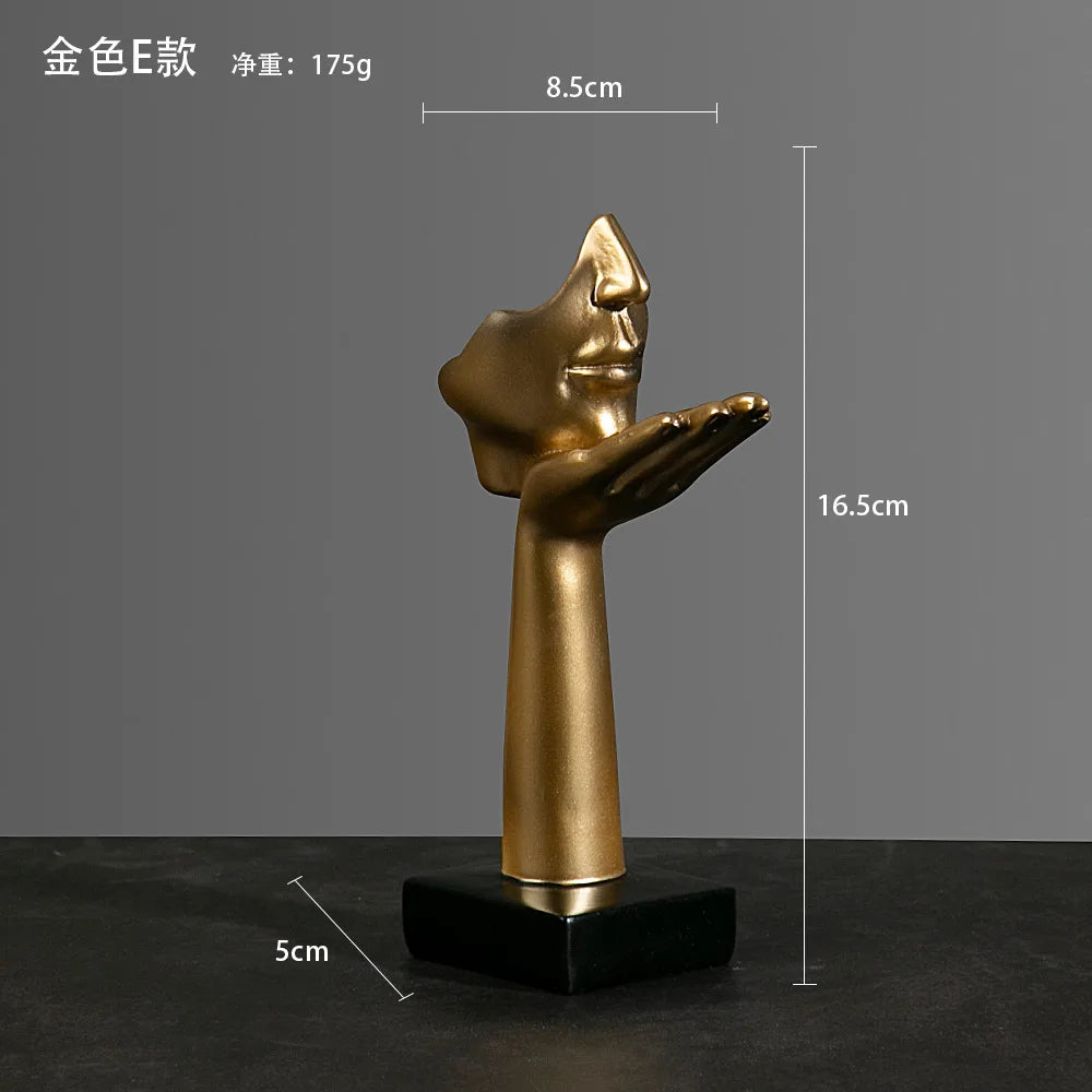 Gold sculpture of a hand and face with measurements:  5cm x 16.5cm x 8.5cm