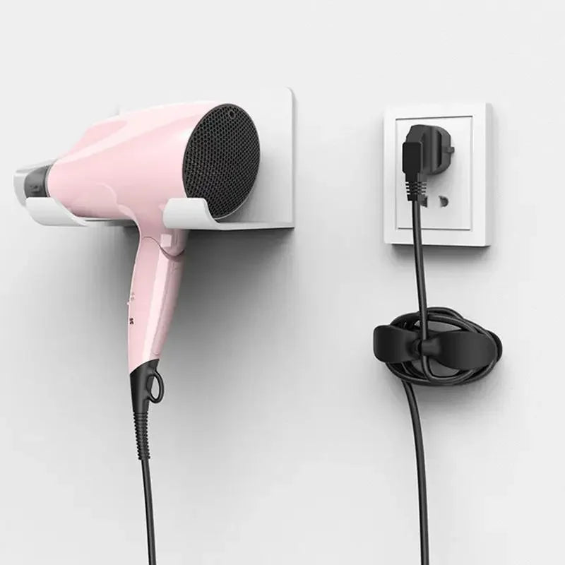 Pink hair dryer attached to a wall socket with a black cord on a white background