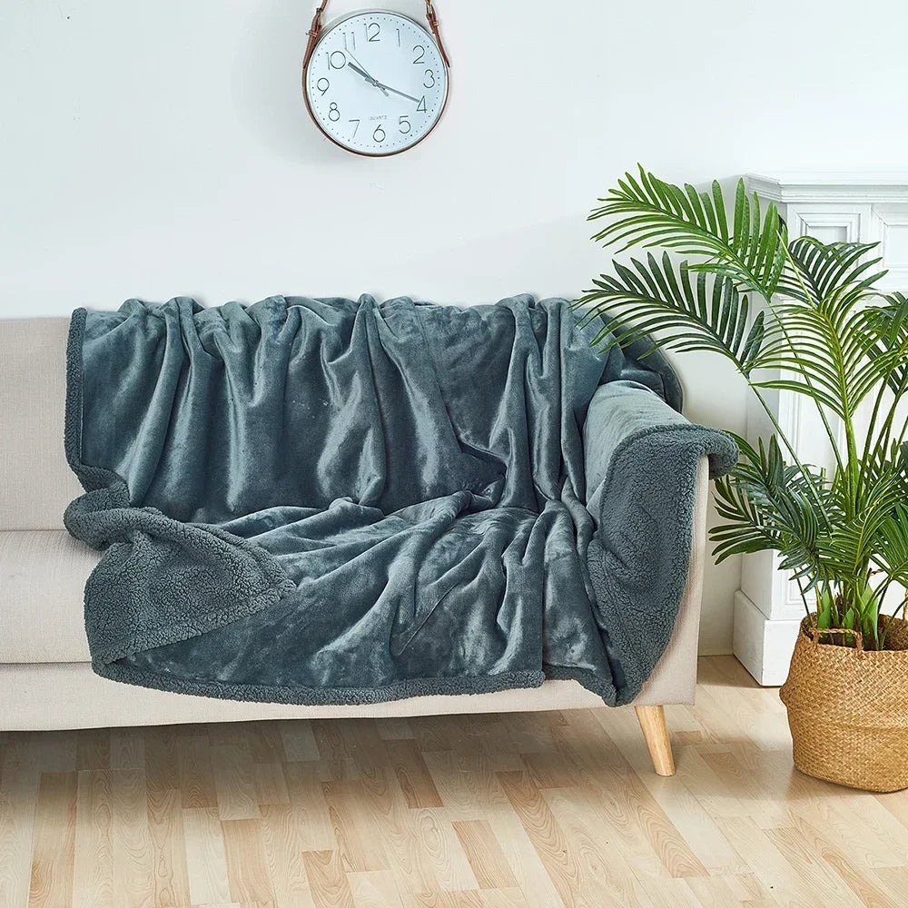 Blue blanket draped over a beige sofa in a living room with a clock and plant in the background.