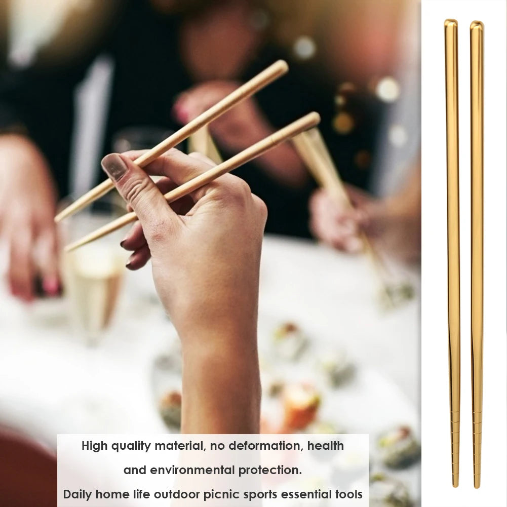 Hand holding golden chopsticks with a blurred background of people and food.