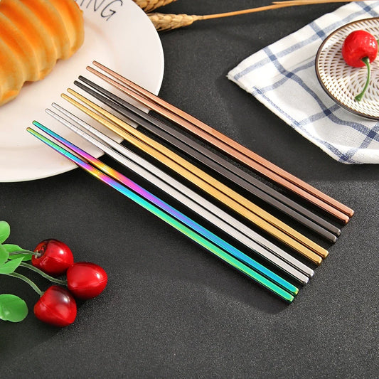 Set of colorful metal chopsticks on a dark surface with decorative elements.