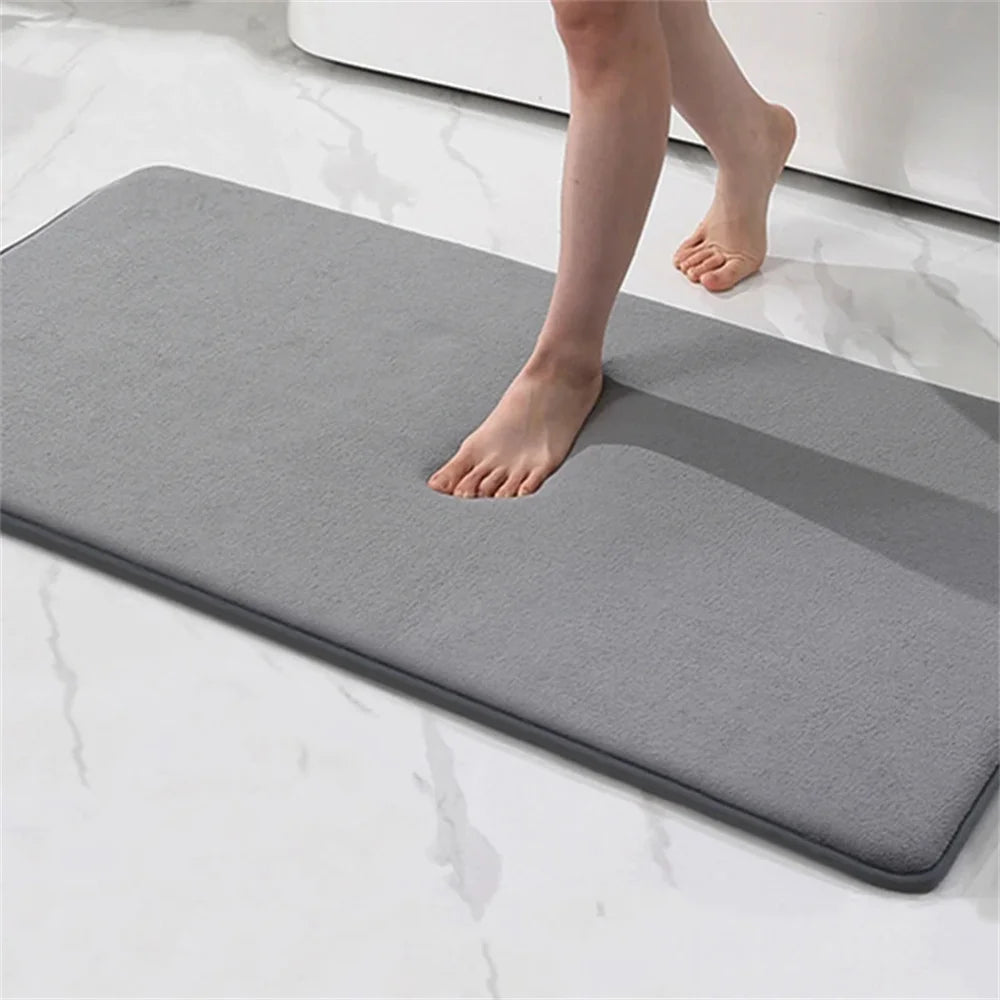 Person stepping onto a gray bath mat on a white surface