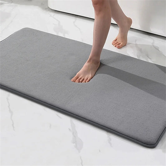 Person stepping onto a gray bath mat on a white surface