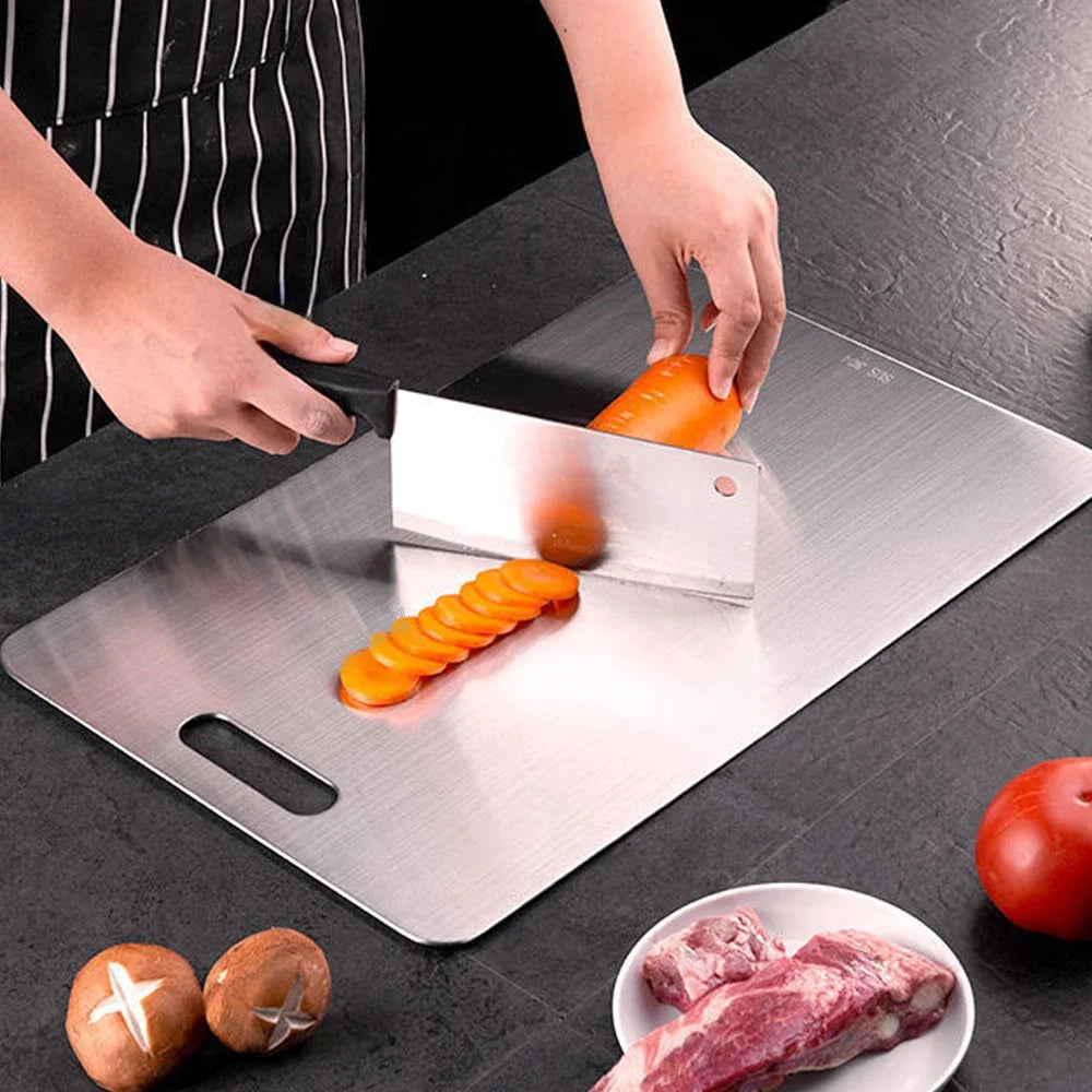 Person cutting vegetables on a stainless steel cutting board with a knife.