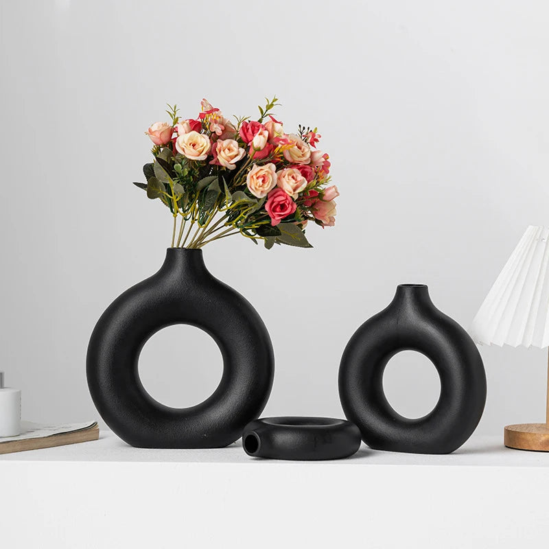 Set of black circular vases with a bouquet of flowers on a light gray background