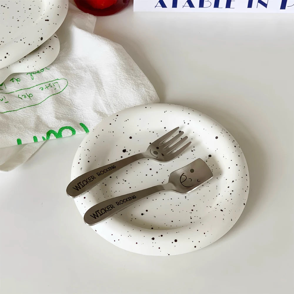 Speckled plate with cutlery on a white surface