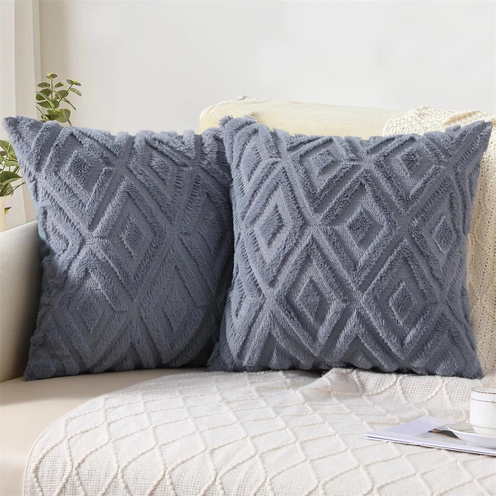 Two gray textured throw pillows on a beige sofa with a white wall background.