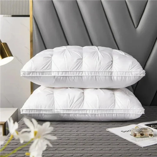 Two white pillows stacked on a bed with a decorative headboard.