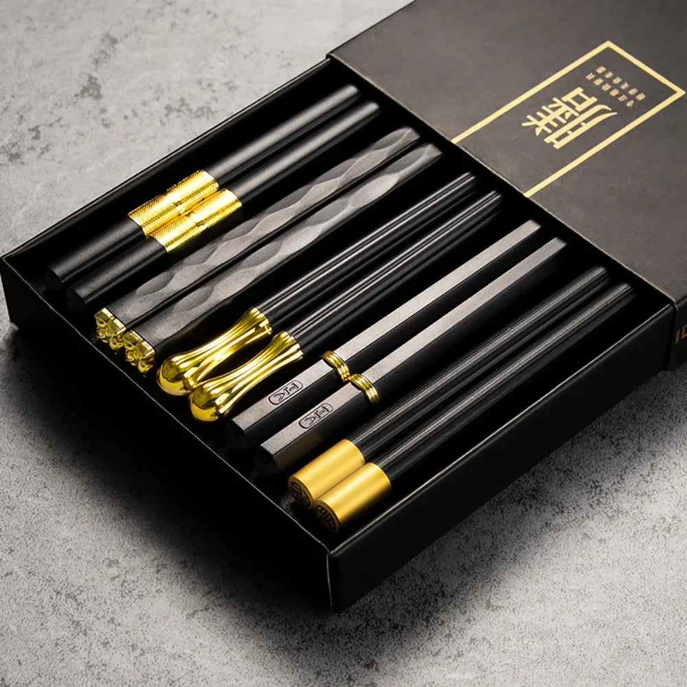 Set of black and gold chopsticks in a black box on a gray surface