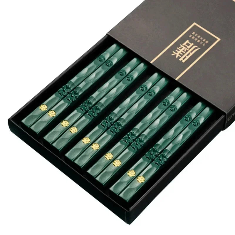 Set of green chopsticks with gold accents in a black box on a white background