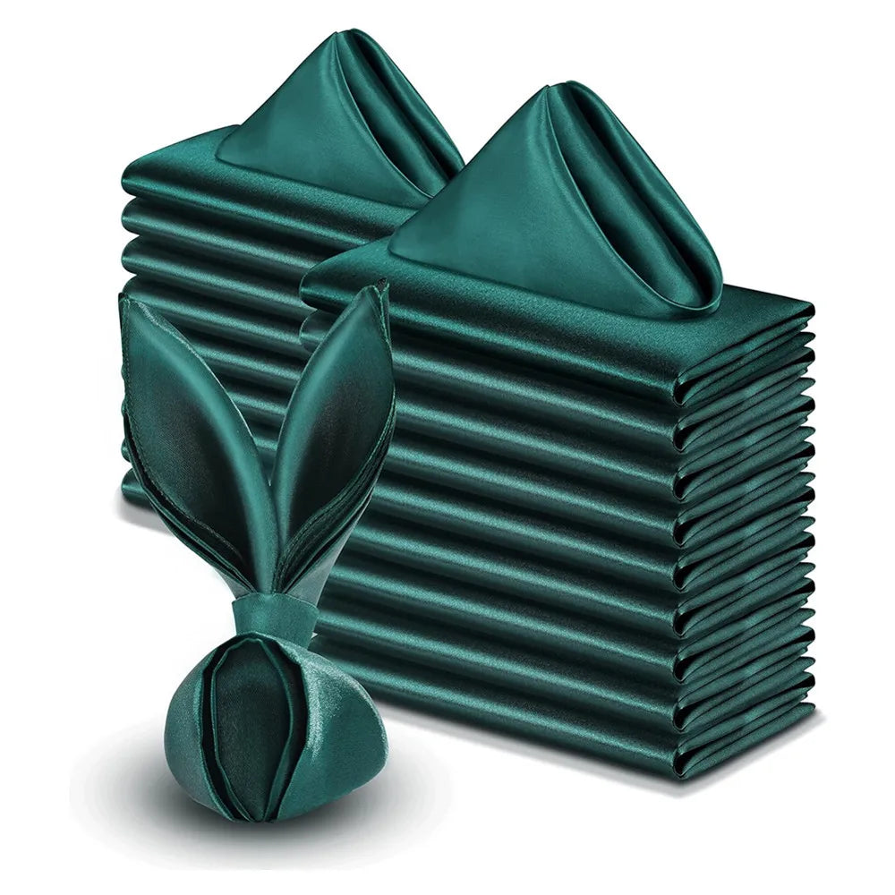Stack of dark green satin napkins with a folded one in front on a white background