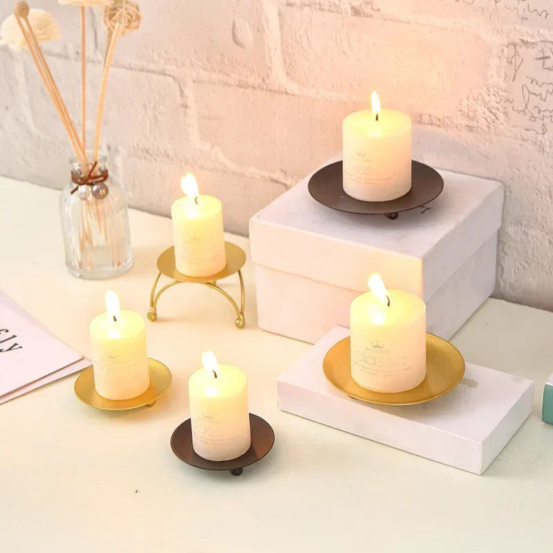 Candles on small stands on a white surface with a light background