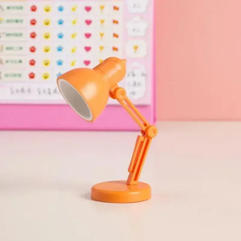 Orange desk lamp on a light pink surface with a colorful heart pattern in the background.