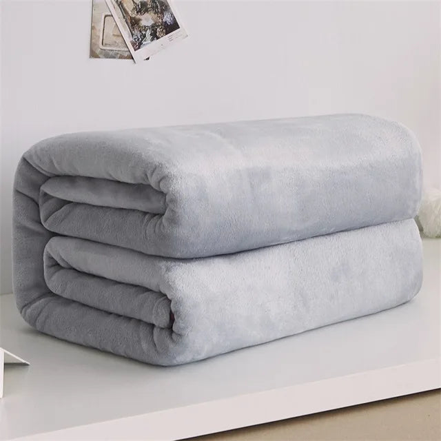 Folded gray blanket on a white surface with a light gray background