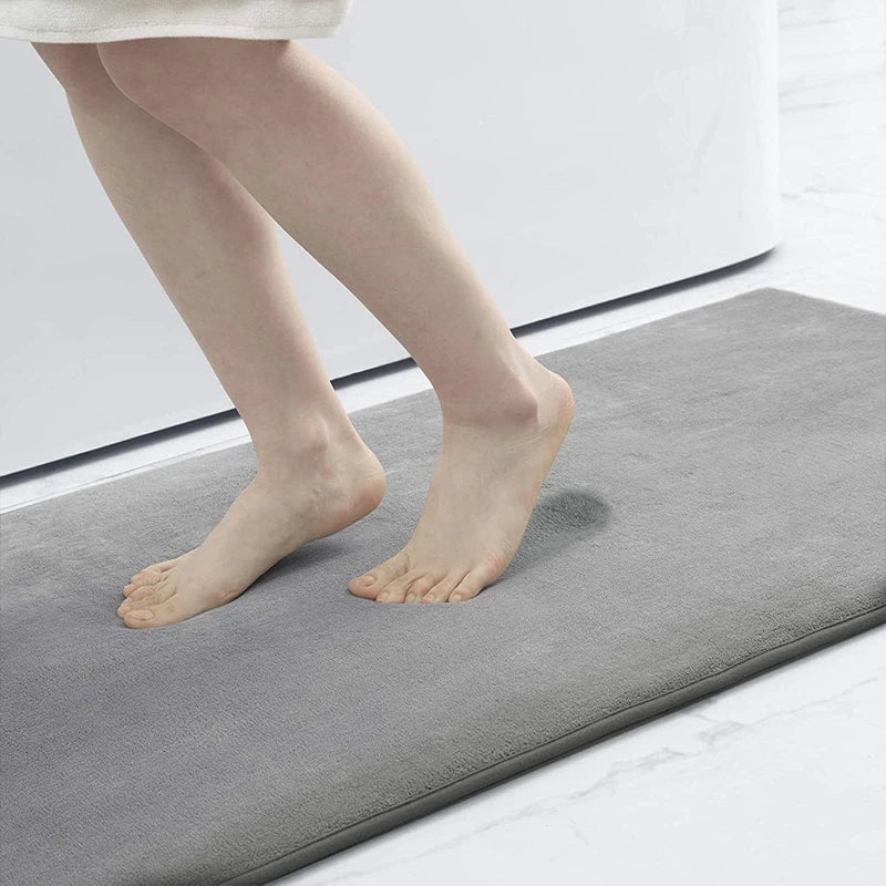 Person stepping onto a gray bath mat with a white background