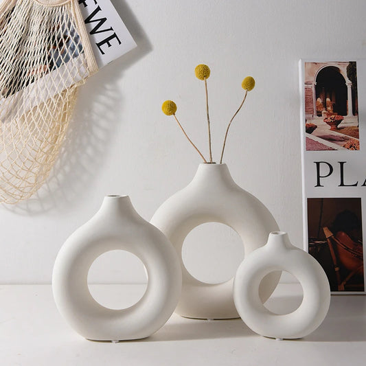 Set of three white ceramic vases with circular designs on a light background
