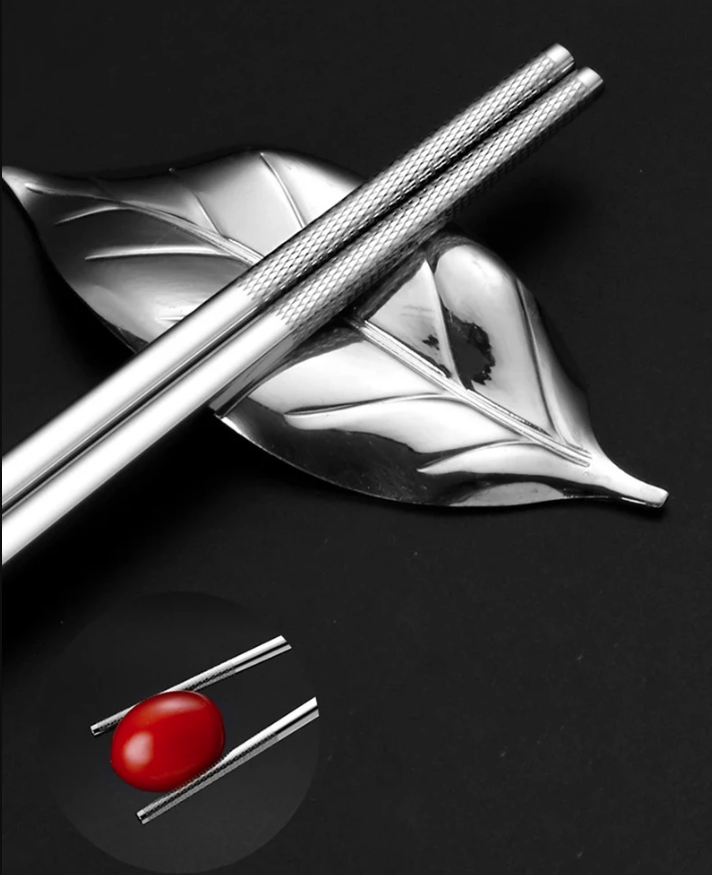 Silver leaf-shaped object with a red sphere on a black background