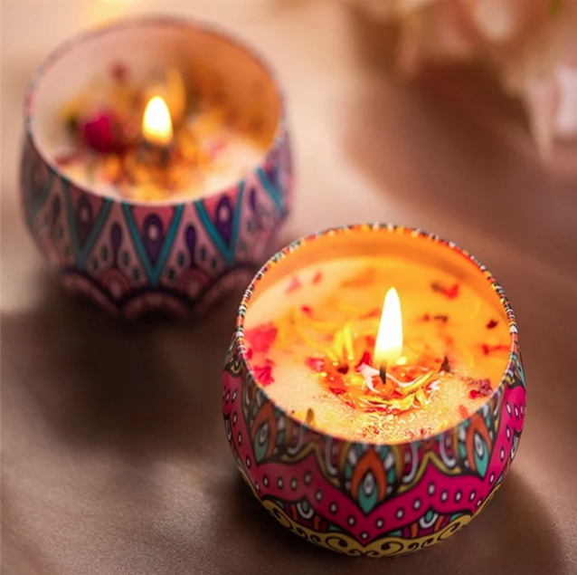 Two colorful candles with flames on a reflective surface.