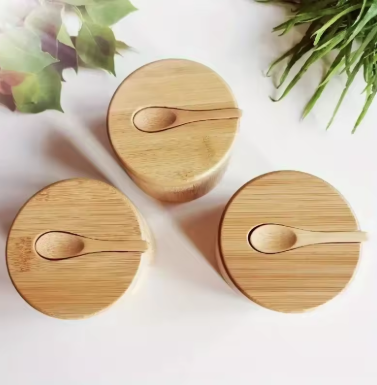 Three wooden containers with lids on a white surface with greenery in the background